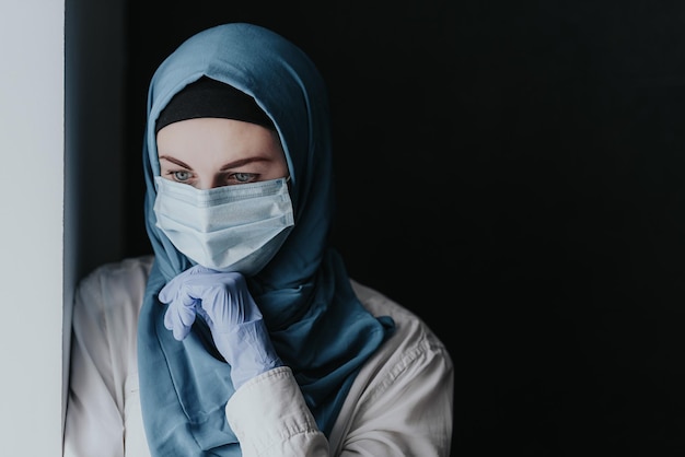 Zmęczony pracownik medyczny lekarz kobieta muzułmanka w hidżabie po przyjęciu dużej liczby pacjentów z powodu epidemii koronawirusa