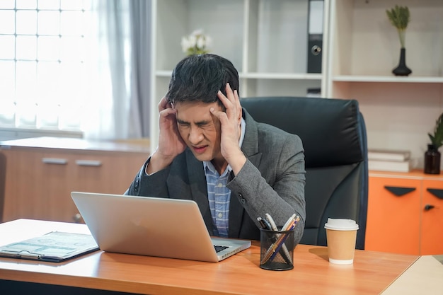 Zmęczony przygnębiony, znudzony i spanikowany biznesmen Zestresowany, pracując we współczesnym biurze, patrząc na laptopa, czuję problem w pracy swobodny strój w miejscu pracy