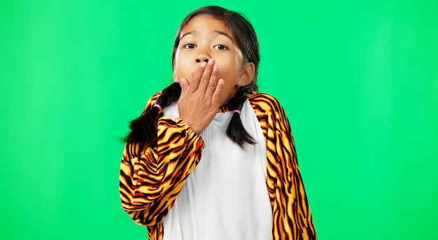 Zmierz się z zielonym ekranem i dziewczyną w kostiumie tygrysa niespodzianką i ręką na ustach na tle studia Portret dziewczynki i młodej osoby z szokującym podekscytowaniem i szczęściem z uroczym dzieckiem i wow