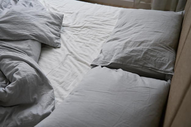 Zmięte łóżko z kocem poduszek i zmiętą pościelą w sypialni