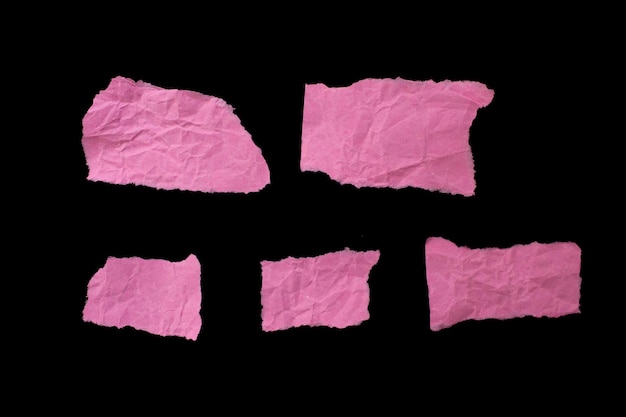 Zmięte podarte różowe kawałki papieru izolowane na czarnym tle