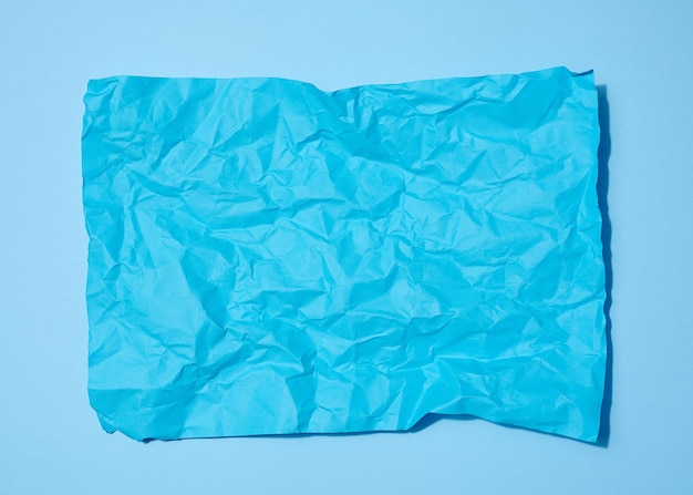 Zmięty prostokątny arkusz niebieskiego papieru na niebieskim tle widok z góry Miejsce na napis