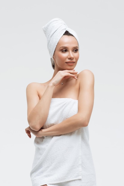 Zmysłowa Kobieta W Puszystym Białym Ręczniku Na Głowie Patrząca Na Palec Dotykający Ręcznika Na Ciele