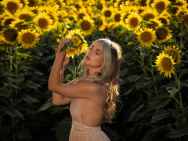 Zmysłowa kobieta ze słonecznikiem w letnim polu
