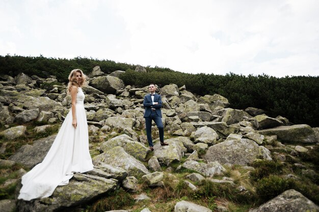 Zmysłowy ślub para stojący na kamienistym brzegu jeziora Sea Eye w Polsce.