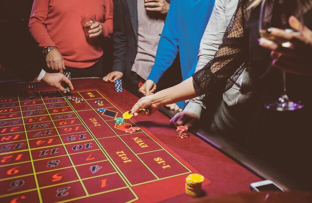 Znajomi ludzie grają w pokera w ruletkę przy stole w kasynie Obróbka zdjęć w stylu vintage
