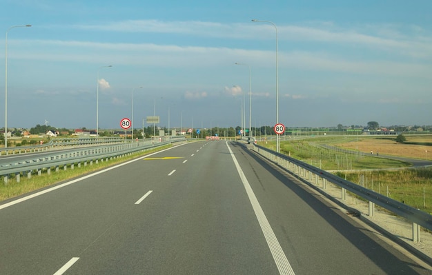 Znak drogowy na autostradzie z ograniczeniem prędkości Widok drogi z samochodu Drogi z oznaczeniami i znakami drogowymi