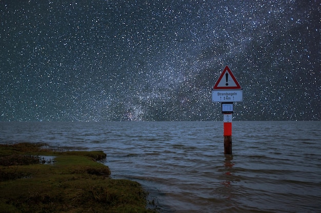 Znak drogowy na morzu na tle nocnego nieba