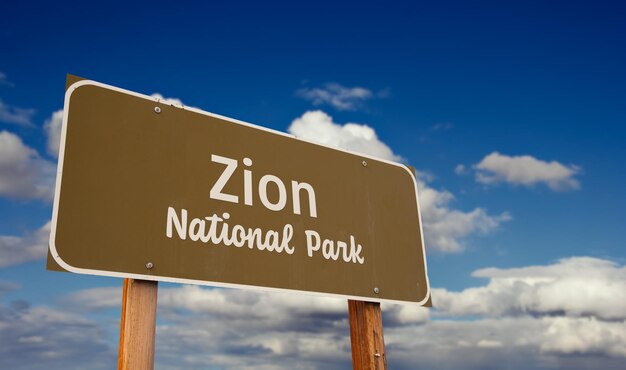 Znak drogowy Parku Narodowego Zion w stanie Utah na tle niebieskiego nieba i chmur