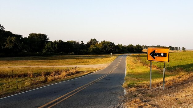 Zdjęcie znak kierunkowy przy pustej drodze wiejskiej na tle nieba