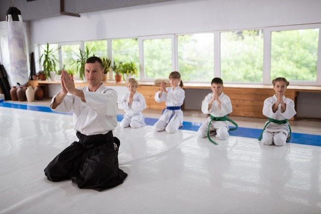 Znak Namaste. Doświadczony Nauczyciel Aikido I Dzieci Wykonujące Znak Namaste Przed Treningiem