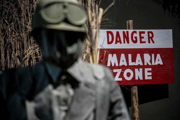 Znak niebezpieczeństwa używany podczas II wojny światowej w obszarach dezynsekcji malarii Obok mężczyzny w mundurze z tamtych czasów z maską gazową