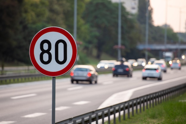 Znak ograniczenia prędkości 80 km h na autostradzie pełnej samochodów