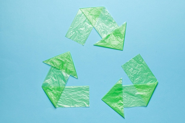 Znak recyklingu plastiku z zielonych toreb na niebieskim tle Zanieczyszczenie środowiska przez recykling toreb