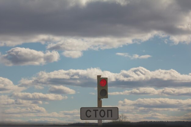 Znak STOP i sygnalizacja świetlna na czerwono na tle chmur i nieba, teleobiektyw
