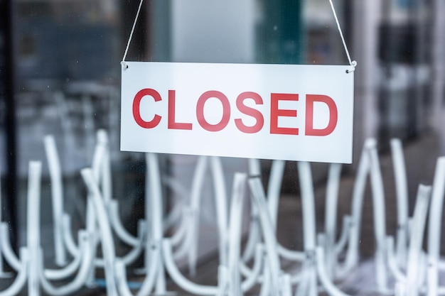 Zdjęcie znak z napisem „zamknięty” wisi na szklanych drzwiach restauracji lub baru