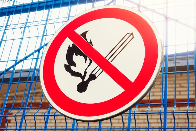 Znak zakazujący rozpoczęcia ognia wisi na metalowym ogrodzeniu Ogień niebezpieczny przedmiot Skrzyżowany mecz Tło