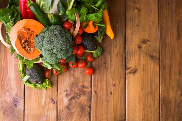 Zdjęcie Żniwa. koncepcja żywności lub zdrowej diety. duży kosz z różnymi świeżymi warzywami gospodarskimi, dynią, brokułami, chard, awokado i pomidorami. skopiuj miejsce selektywne ustawianie ostrości. widok z góry