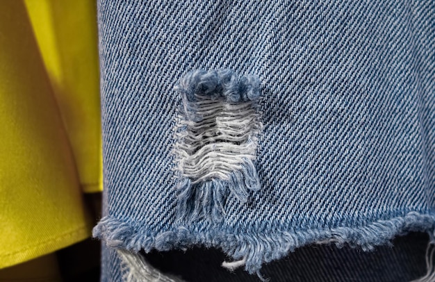 Znoszone niebieskie dżinsy z podartymi dziurami wiszą w szafie.