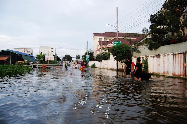 Zobacz pejzaż krajobrazu miasta Bang Bua Thong podczas powodzi i drogi zalewowej z tajlandzkimi ludźmi czekającymi na pomoc ratowniczą i darowizny na wsi wiejskiej 20 października 2011 r. w Nonthaburi Tajlandia
