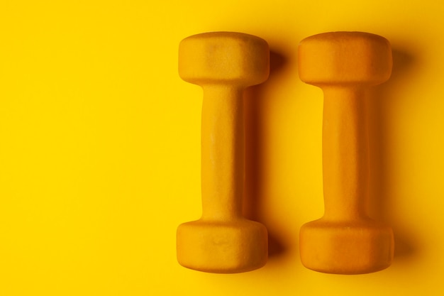 Żółci dumbbells na żółtym tle