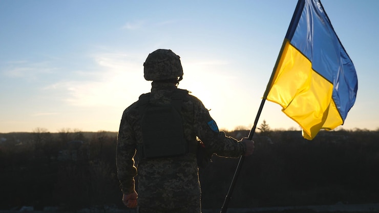 Zdjęcie żołnierz armii ukraińskiej trzymający flagę ukrainy na tle zachodu słońca mężczyzna w mundurze wojskowym i hełmie podniósł flagę zwycięstwo przeciwko rosyjskiej agresji koncepcja odporności na inwazję