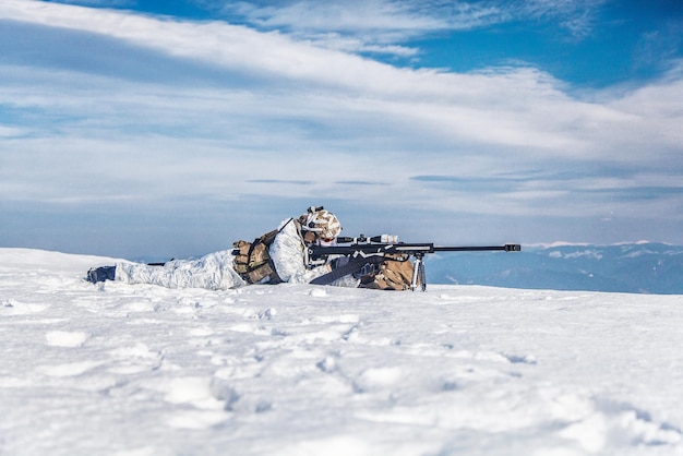 Żołnierz armii z karabinem snajperskim w akcji w Arktyce. Leży na śnieżnej pustyni, cierpi z powodu ekstremalnego zimna, ale czeka, aż wrogowie pojawią się, aby ich zabić