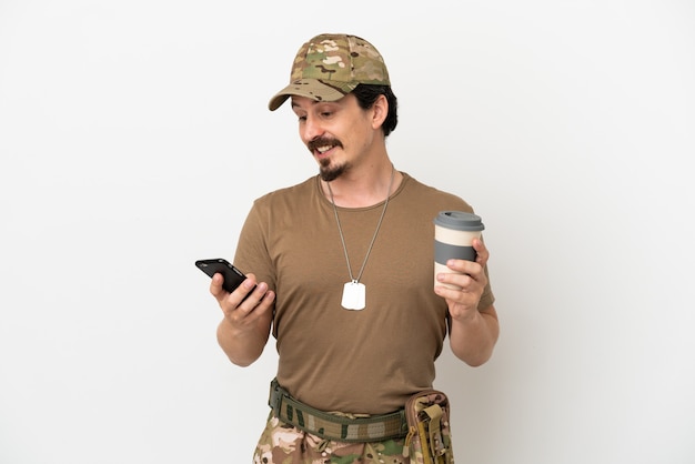 Żołnierz na białym tle trzymający kawę na wynos i telefon komórkowy