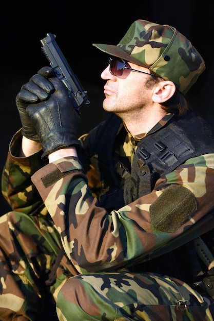 Żołnierz w mundurze trzyma pistolet.