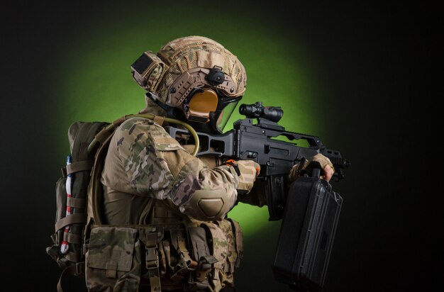 Żołnierz w wojskowym stroju z bronią na ciemnym tle w masce gazowej