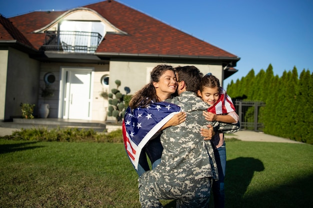 Zdjęcie Żołnierz wraca do domu i jego rodzina z amerykańską flagą wpadająca mu w ramiona świętuje spotkanie