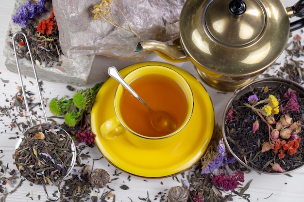 Zdjęcie Żółta filiżanka herbaty stoi na stole obok imbryka i imbryka z kompozycją kwiatową.