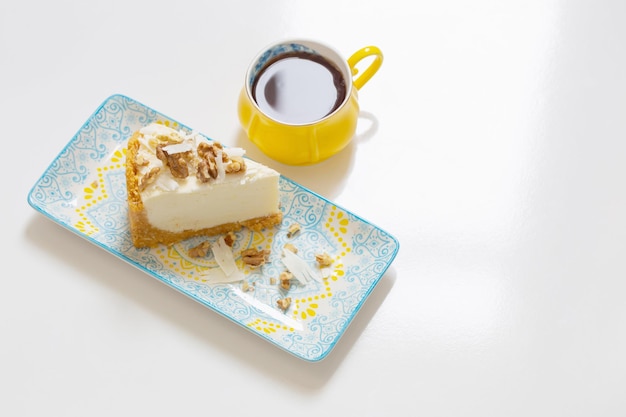 Żółta filiżanka kawy z sernikiem na białym stole