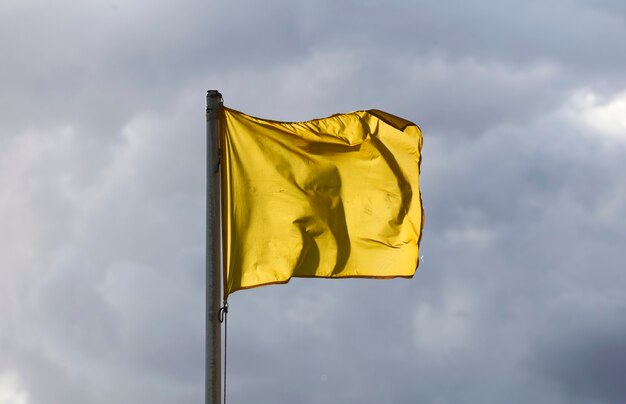 Zdjęcie Żółta flaga leci w powietrzu z chmurami