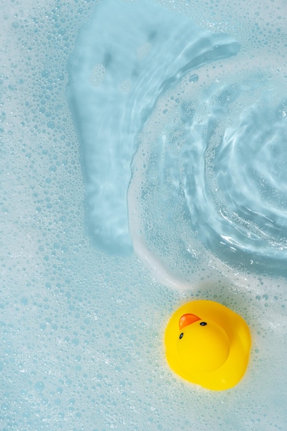 Zdjęcie Żółta gumowa kaczka pływająca na niebieskiej wodzie kąpiąc się i pływając