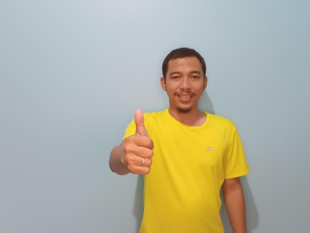 Zdjęcie Żółta koszulka azjatyckiego mężczyzny kciuk w górę