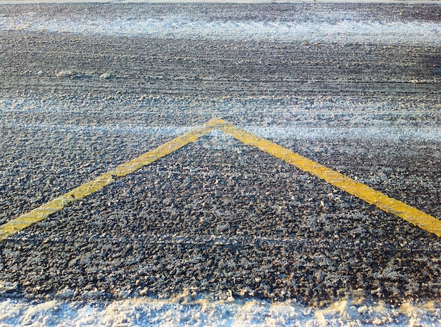 Żółta linia oznakowania na zimowym tle drogi