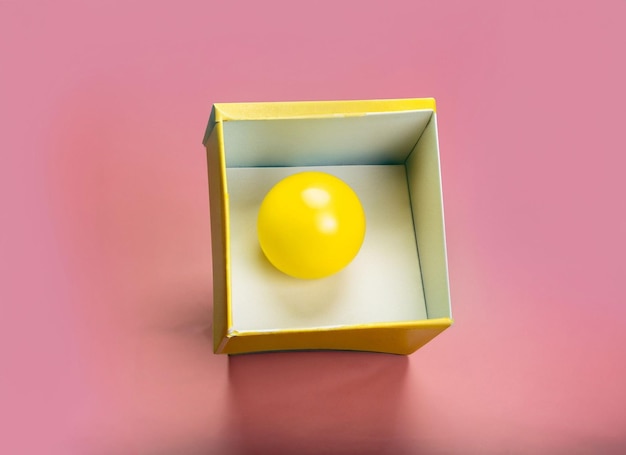 Żółta piłka w pudełkukoncepcje prezentów lub niespodzianekśmieszne tło