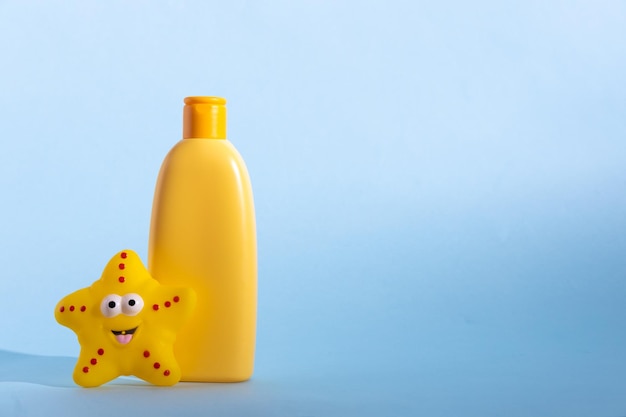 Zdjęcie Żółta plastikowa butelka z kosmetykami dla dzieci i zabawną zabawką do kąpieli koncepcja pielęgnacji skóry dla dzieci