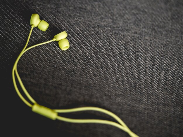 Zdjęcie Żółte earbuds na ciemnobrązowej kanapy tle.