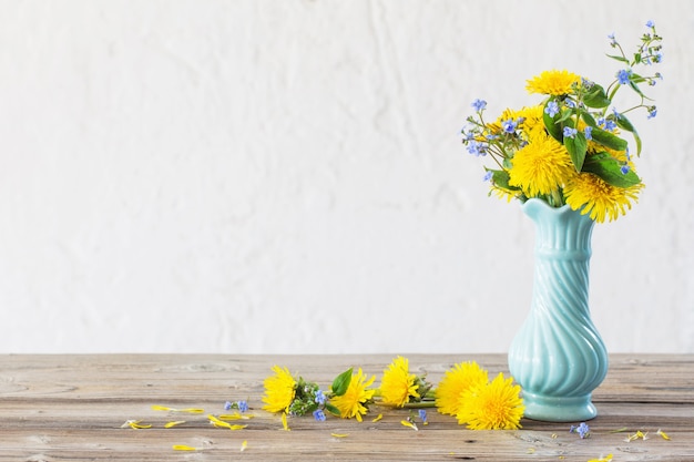 Żółte i niebieskie wiosenne kwiaty w niebieskim wazonie na białym tle