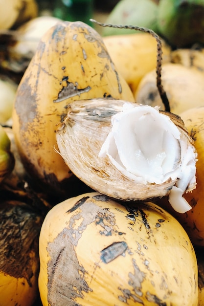 Żółte kokosy są sprzedawane na targu na wyspie Mauritius. Pokrój młodego kokosa za pomocą Makoto. Wiele kokosów na rynku.