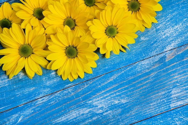 Żółte kwiaty na pomalowanym drewnianym tle tekstu