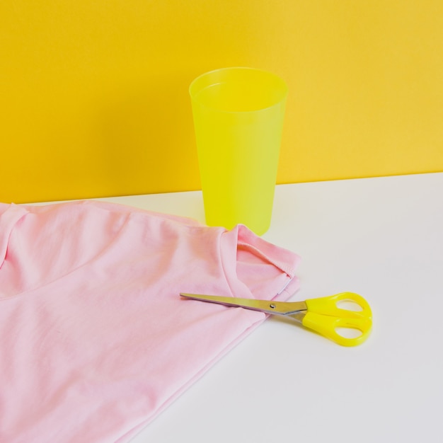 żółte nożyczki na różowej koszulce z plastikowym szkłem w kreatywnej koncepcji