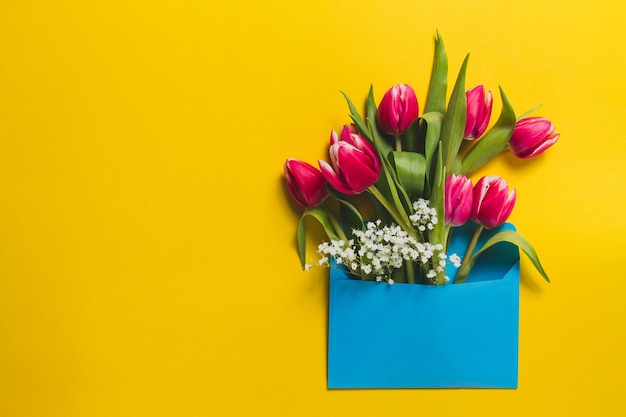 Żółte tło z niebieską kopertę i tulipany