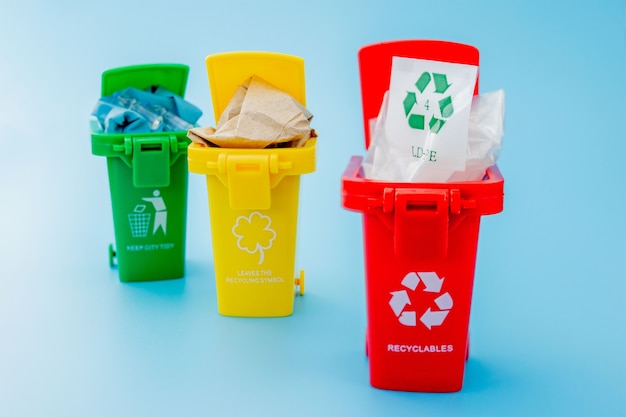 Żółte, zielone i czerwone kosze do recyklingu z symbolem recyklingu na niebiesko