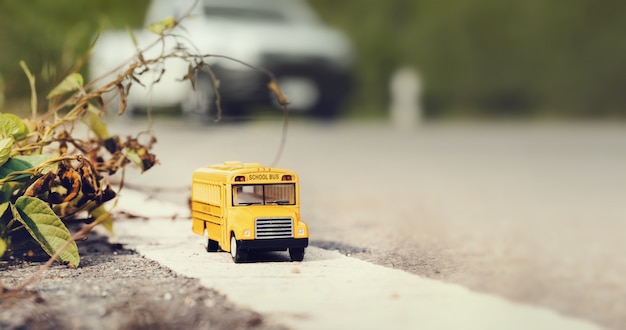 Żółty autobus szkolny zabawka model na wiejskiej drodze.