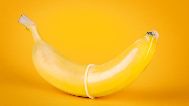 Żółty banan i prezerwatywa na żółtym tle Koncepcja bezpiecznego seksu