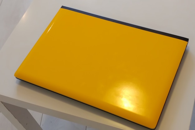 Żółty błyszczący laptop na białym drewnianym stole