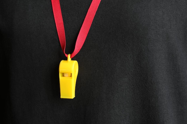 Żółty gwizdek z czerwonym sznurkiem zawieszony na koszulce sędziego
